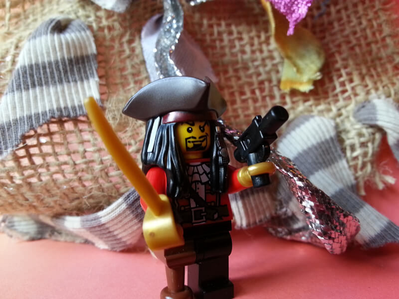 A lego pirate figure with a cutlass, pistol, tricornered hat, peg leg, long hair and beard.