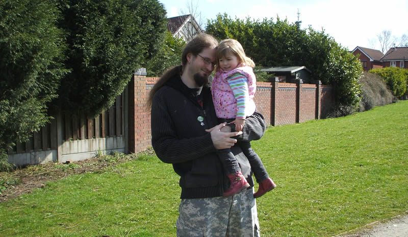 Chris standing up holding his daughter Elva