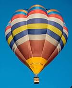 An orange hot air balloon as seen from below